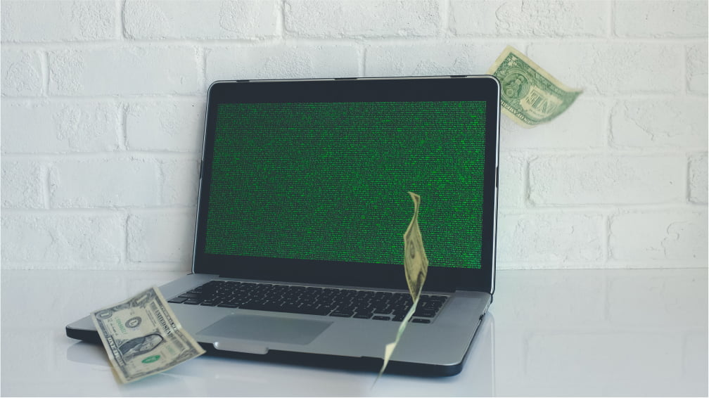 Laptop with dollar bills falling around it
