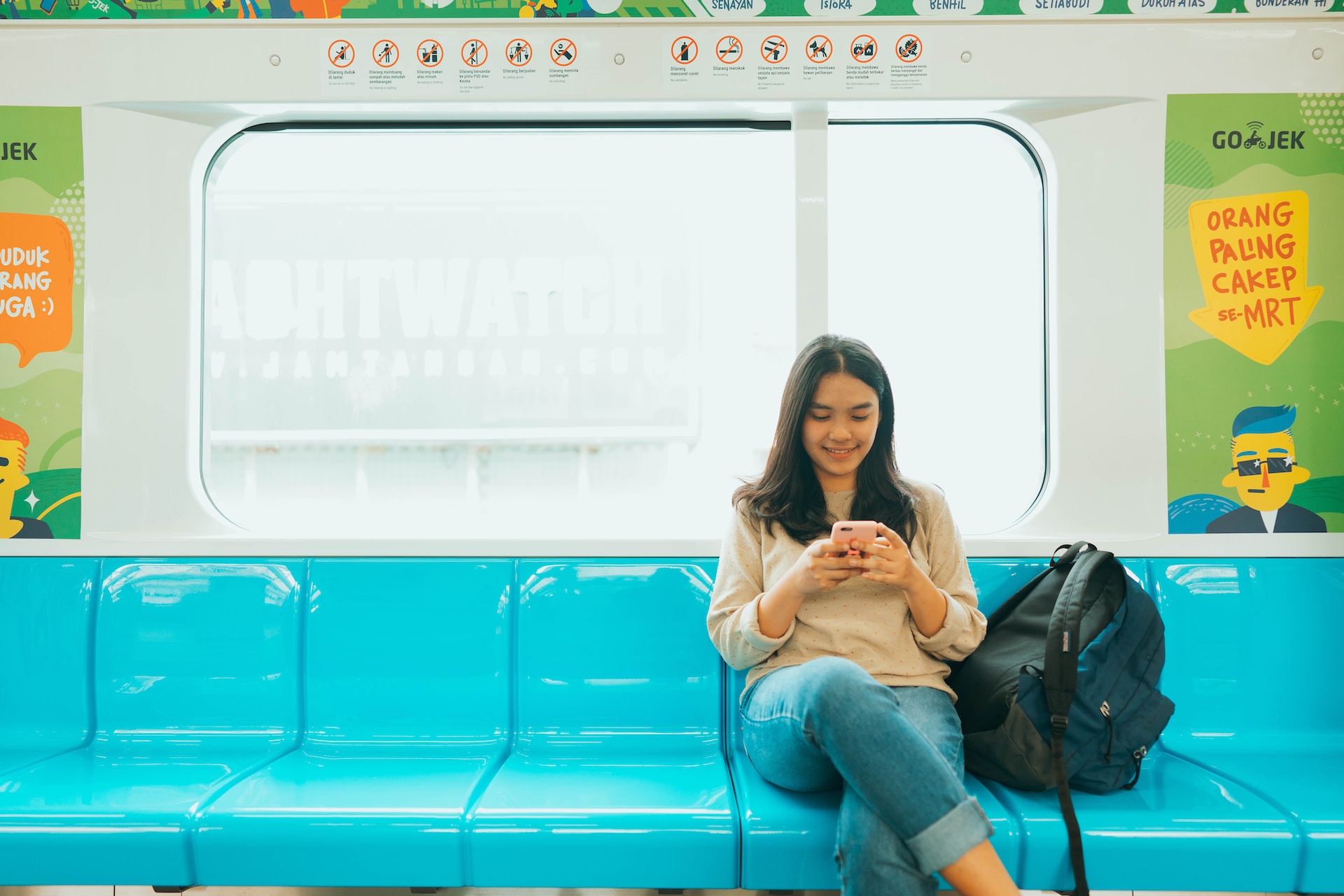 Woman sitting and smiling while using her phone