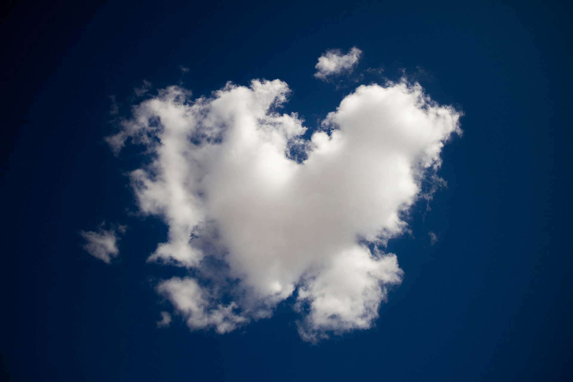 A white heart-shaped cloud in a blue sky.